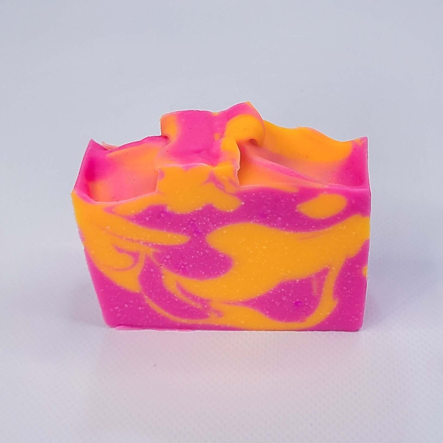 Vibrant pink grapefruit soap bar with swirling orange hues, offering a refreshing and uplifting citrus cleanse for smooth, hydrated skin.