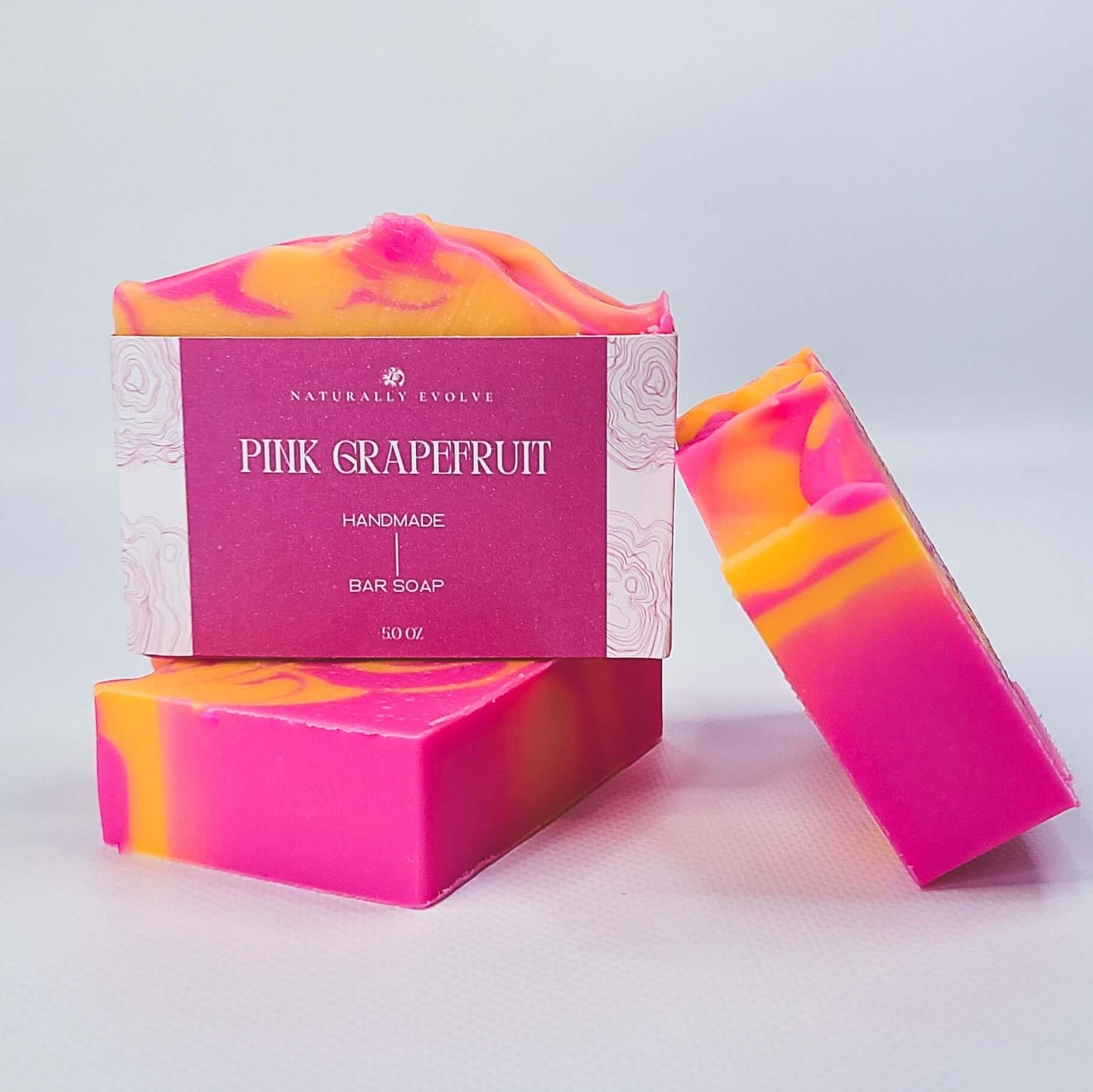 Vibrant pink grapefruit bar soap with citrus scent, perfect for a refreshing and uplifting morning shower.